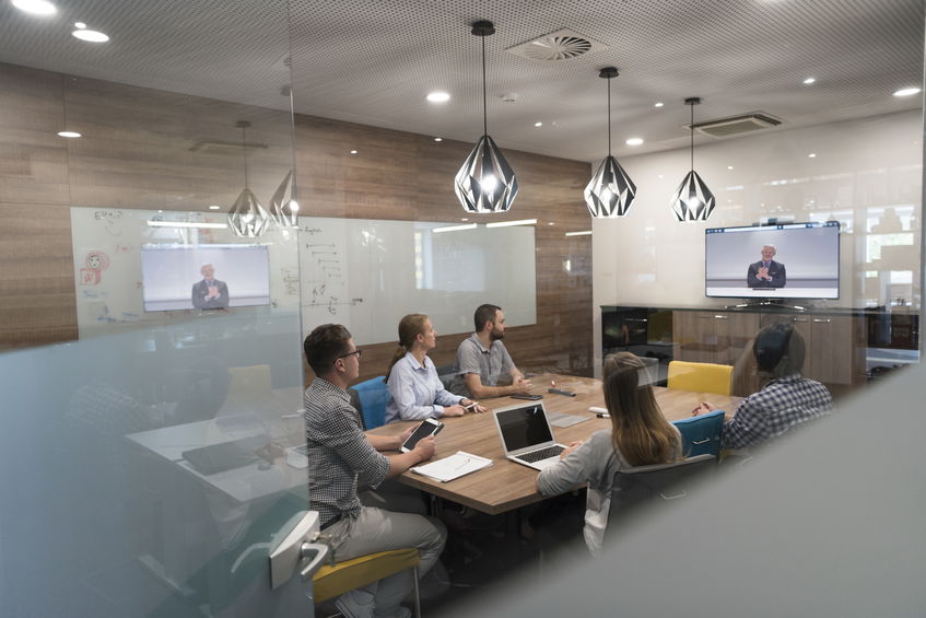 a group of employees video conferencing in a set area, showing good video conferencing etiquette